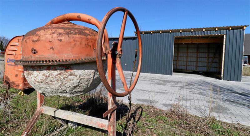Eine Betonmischmaschine vor einer sich im Bau befindlichen kleinen Halle.