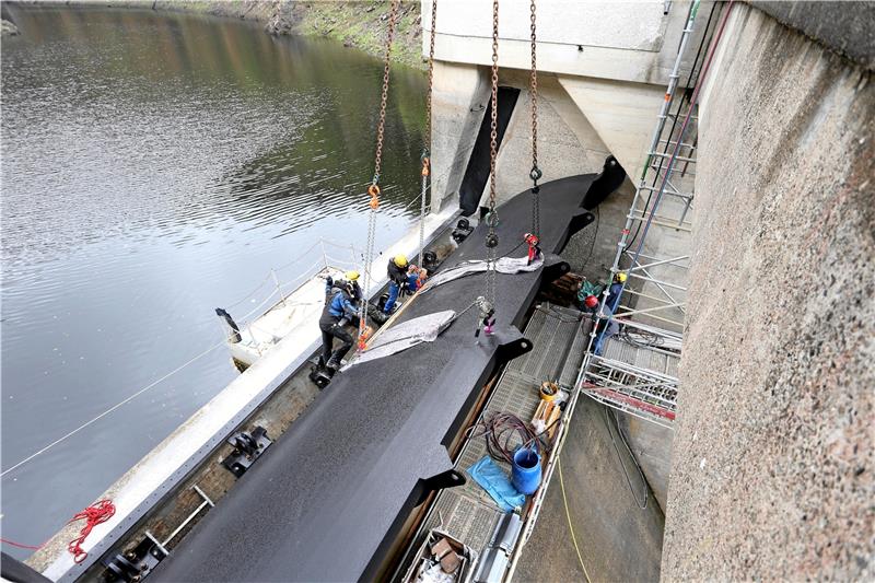 Okertalsperre: Neue Wehrklappe ist da Die neue Wehrklappe hängt am Kran über der Staumauer. Mitarbeiter der Karstädter Fachfirma passen das Tor in die dafür vorgesehene Öffnung ein. Fotos: Neuendorf