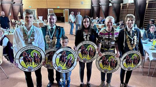 Die neuen Majestäten (v.l.) Stadtjugendkönig Steven Ortlieb, Stadtkönig Michael Emmler, Stadtschülerkönig Fynn Hertrampf, Volkskönigin Valeria Santo, Ratskönigin Gesine Kirschke und Stadtkönigin Petra Walter mit den Ehrenscheiben, die in diesem Jahr ein Motiv der Galopprennwoche zeigen. Gestiftet wurden sie von den Stadtwerken, der Rennverein spendierte dazu noch Eintrittskarten.