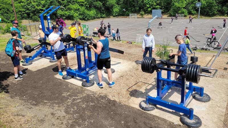 Braunlage hat ein neues Outdoor-Fitnessstudio Die neuen Sportgeräte werden bei ihrer offiziellen Übergabe gleich eifrig genutzt. Auf dem Platz im Hintergrund wird parallel Hockey gespielt.