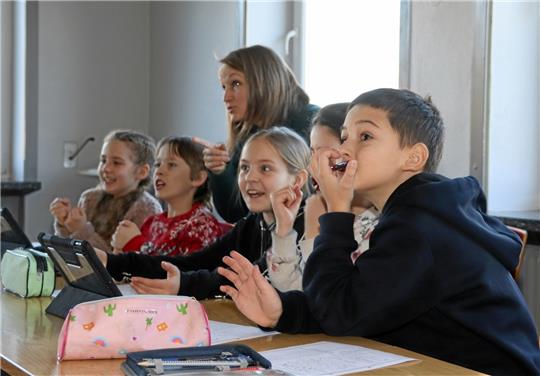 Die ukrainischen Flüchtlingskinder Olga, Vova, Kristina, Nadiia und David (v. li) nehmen dank der Unterstützung der ebenfalls hierher geflüchteten Sprachhelferin Anja Virshke begeistert am Sachunterricht der vieren Klasse teil und lernen in einer Schulstunde Niedersachsen und Deutschland in Form eines Quiz per App am Tablet näher kennen. Foto: Jambrek