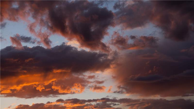 Die untergehende Sonne lässt die Wolken über Köln rötlich schimmern.