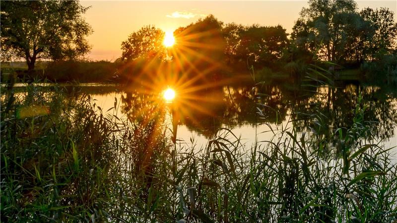 Bilder des Tages Die untergehende Sonne spiegelt sich in einem kleinen See im östlichen Brandenburg.