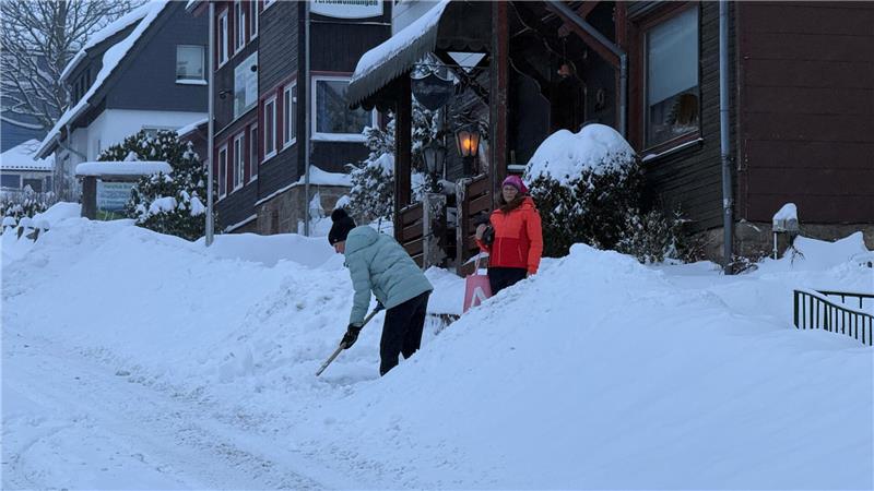 Das Foto zeigt eine Frau, die Schnee schippt, und eine, die sich mit ihr unterhält.