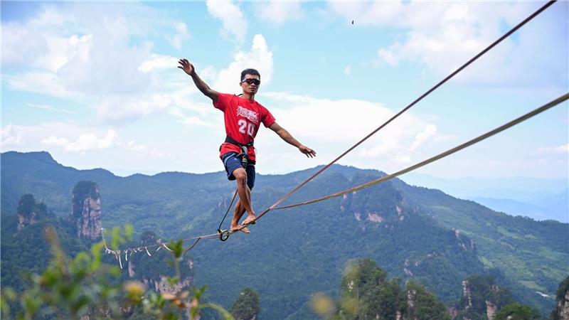 Bilder des Tages Dieses Drohnenfoto zeigt den den Chinesen He Jinyi bei der „Slackline-König“-Meisterschaft 2025 im malerischen Ort Huangshizhai im Zhangjiajie Nationalpark in der zentralchinesischen Provinz Hunan.