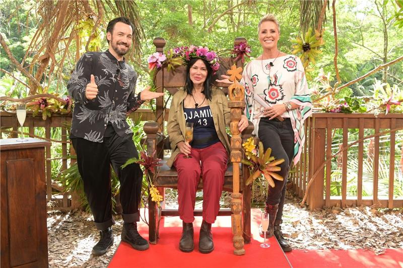 Djamila Rowe sitzt nach dem Sieg beim RTL-Dschungelcamp 2023 mit ihrer Krone auf ihrem Thron. Neben ihr stehen Moderatorin Sonja Zietlow (r) und Moderator Jan Köppen.