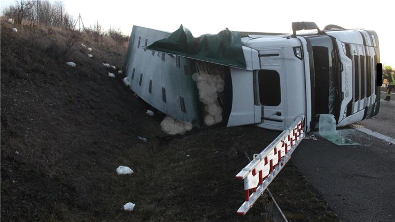 Ein Lkw liegt auf der Autobahn seitlich in einem Graben. 