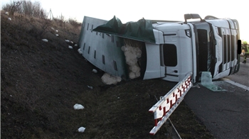 Ein Lkw liegt auf der Autobahn seitlich in einem Graben. 