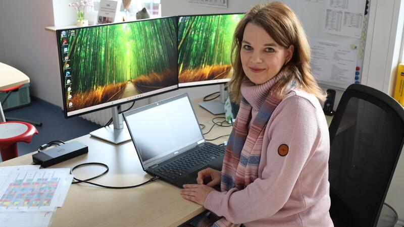 Eine Frau sitzt an ihrem Schreibtisch.