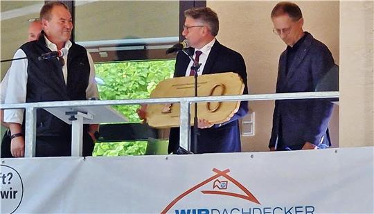 Dr. Frank Biermann (Mitte) übergibt den symbolischen Schlüssel an den technischen Geschäftsführer Dachdeckermeister André Hannes (l.)