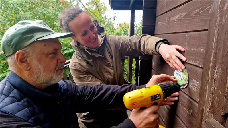 Wie Gartenbesitzer Schlafmäusen das Leben retten können Dr. Friedhart Knolle als Vorsitzender des BUND-Regionalverbands Westharz und Dr. Jeannette Lex montieren die neue „SchlaGa“-Plakette in dem Zellerfelder Garten.