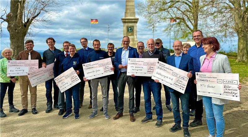 Rotary-Club übergibt Spenden an sieben Organisationen Dr. Thomas Stumpf (3.v.l.) und Rotary-Präsident Burkhard Naffin (Mitte) überreichen im Schatten der Canossa-Säule die Schecks an Vereine und Organisationen, damit sie damit Jugendarbeit leisten können. Foto: Schlegel