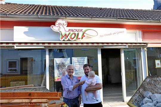 Drei Generationen Bäcker Wolf: Die beiden Geschäftsführer Rüdiger (74) und Christian (36) freuen sich mit der neun Monate alten Tochter beziehungsweise Enkelin Carlotta über den Start des Umbaus. Foto: Heine