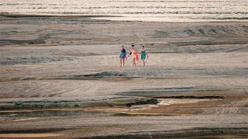 Drei Menschen spazieren in Rumänien über freigelegte Sandbänke der Donau