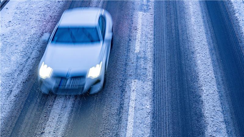 Ein Auto fährt über eine schneebedeckte Straße.