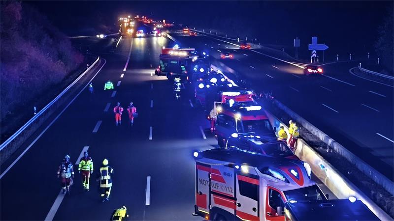 Nächtliche Autobahnszene mit mehreren Einsatzfahrzeugen und Einsatzkräften auf der Fahrbahn