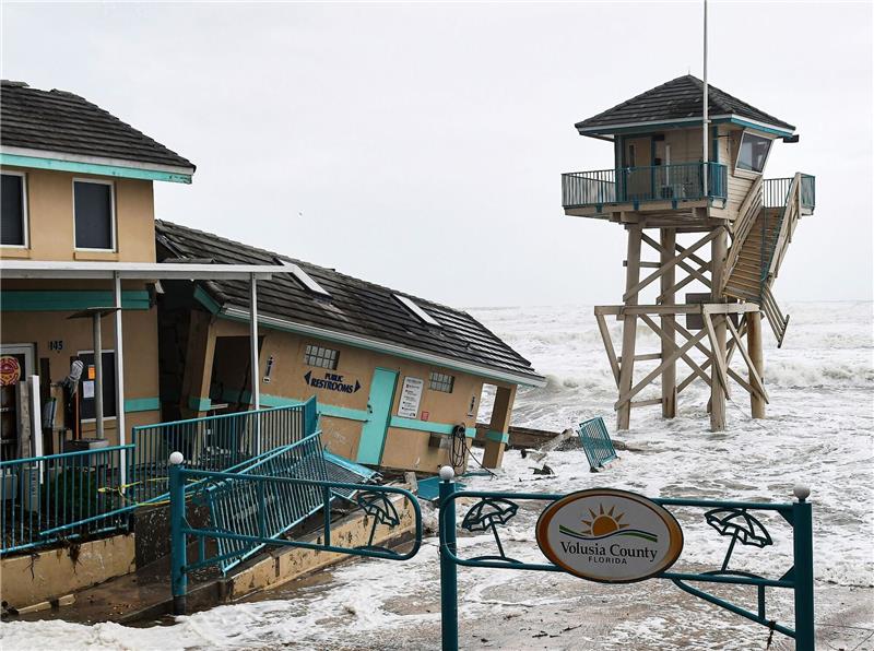 Durch den herannahenden Sturm «Nicole» verursachte Wellen schlagen in der Nähe eines beschädigten Gebäudes und eines Rettungsschwimmerturms auf.