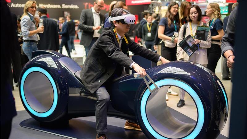 Durch eine Augmented-Reality-Brille schauend sitzt ein Gast auf einem fiktiven Gefährt bei der Industriemesse Hannover.