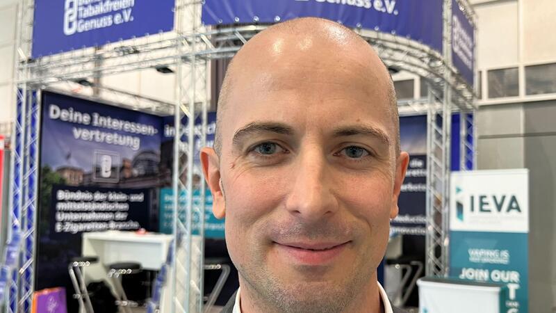 Dustin Dahlmann, Vorsitzender des E-Zigaretten-Verbandes „Bündnis für Tabakfreien Genuss“ (BfTG), steht bei der Messe Intertabac 2023 vor einem Stand seiner Organisation.