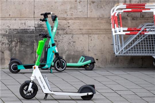 E-Scooter von Lime, Tier und Bolt stehen in Berlin auf einem Gehweg.