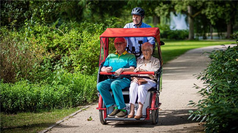 Ehrenamtliche unternehmen mit den Rikschas Ausflüge mit älteren Menschen.