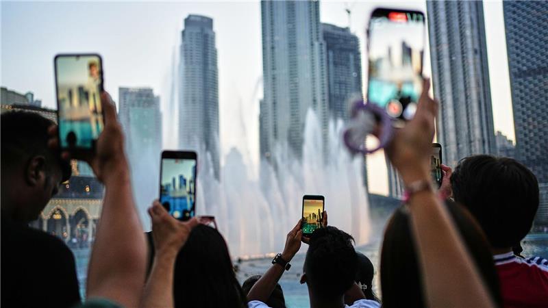 Eid al-Adha in Dubai: Besucher fotografieren den Brunnen vor der Skyline
