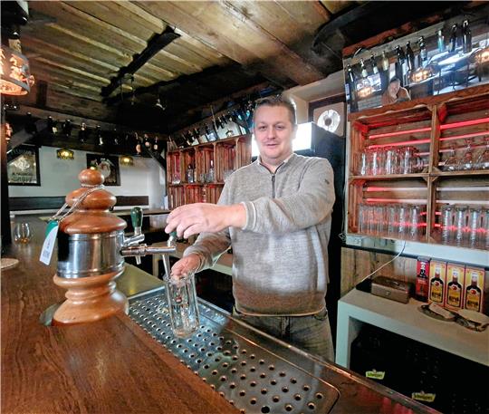 Eigentümer Matthias Holthuis fühlt sich hinter der Theke wohl. Im alten Backhaus hat er die Kneipe wiedereröffnet. Foto: Knoke