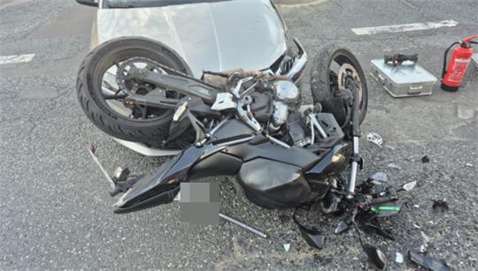 Ein zerstörtes Motorrad liegt auf der Motorhaube eines silbernen Autos.
