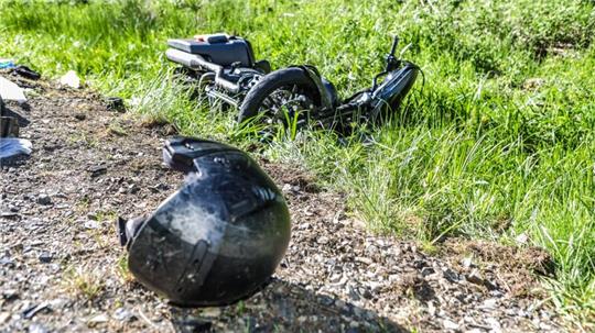 Das Foto zeigt ein kaputtes Motorrad im Straßengraben und einen Helm.