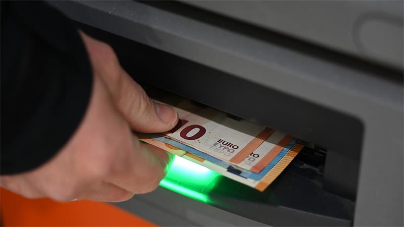 Hand zieht einen 50-Euro-Schein aus einem Geldautomaten