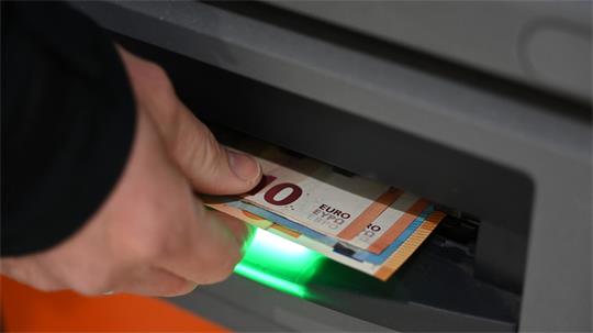 Hand zieht einen 50-Euro-Schein aus einem Geldautomaten