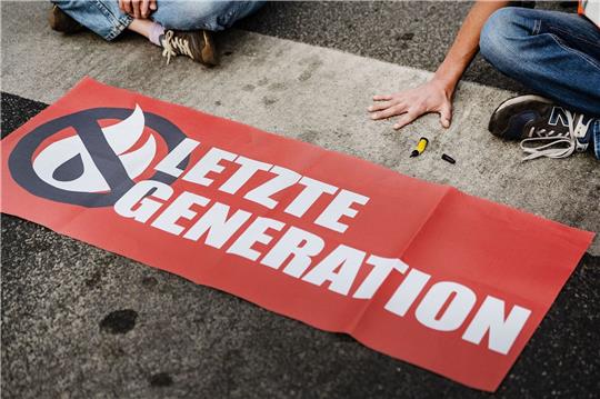 Ein Aktivist der Letzten Generation klebt seine Hand auf einer Straße fest. Solche Klebeaktionen hat die Gruppe inzwischen aufgegeben - und nun eine Kandidatur für das Europaparlament angekündigt (Archivbild).