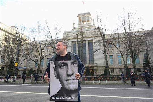 Ein Aktivist steht mit einem Plakat von Kremlkritiker Alexej Nawalny vor der russichen Botschaft in Berlin und protestiert.