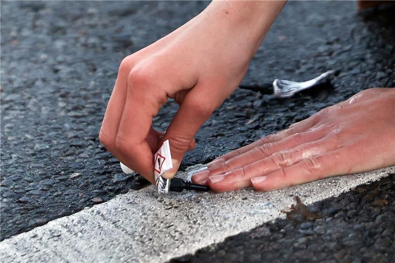 „Letzte Generation” kündigt Unterbrechung der Proteste an Ein Aktivist von «Letzte Generation» klebt seine Hand mit Sekundenkleber auf der Straße in Berlin während einer Sitzblockade fest.