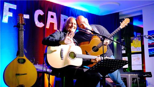Ein Angebot, das der Fotograf nicht ausschlagen kann: Peter Kerlin (li.) und Jens Kommnick machen alles mit und bestreiten in der familiären Atmosphäre eines Wohnzimmerkonzerts auf den „Höfen“ ein Konzert zum Mitgehen und Wegträumen.  Foto: Zietz