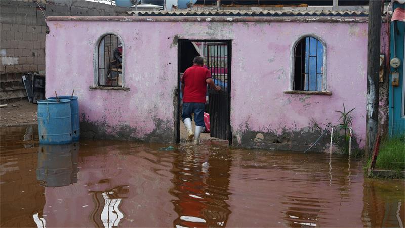 Ein Anwohner betritt sein Haus, das nach dem Durchzug vom Hurrikan „Polo“ in Puerto San Carlos in Mexiko im Wasser steht.