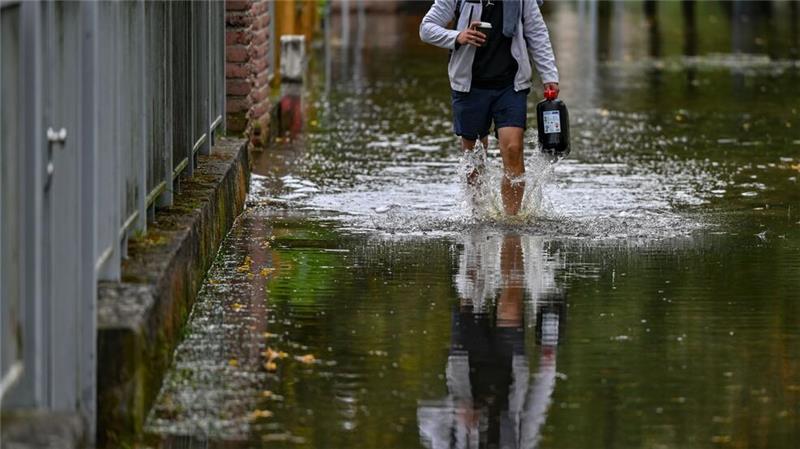 Trotz fallender Pegel: Hochwasserlage angespannt Ein Anwohner einer überfluteten Straße in Frankfurt Oder watet durch das Wasser.