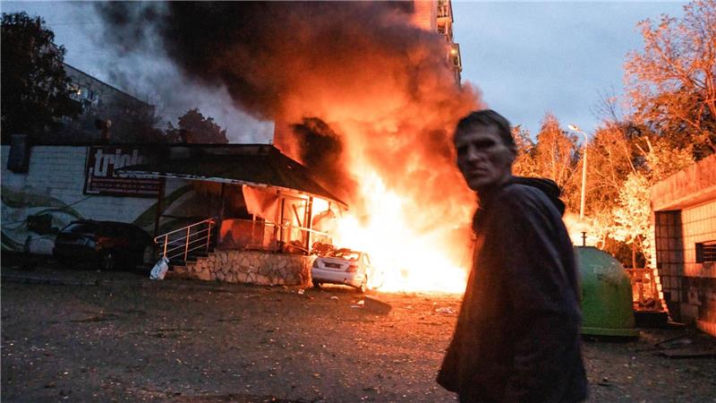Ein Anwohner geht nach einem Luftangriff in Kiew an einem Feuer vorbei.