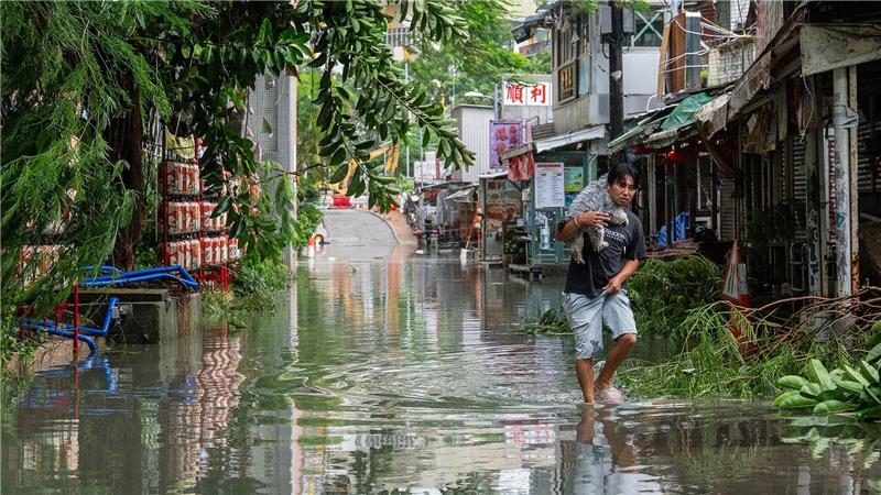 Ein Anwohner trägt in Hongkong ein Haustier durch das Hochwasser.