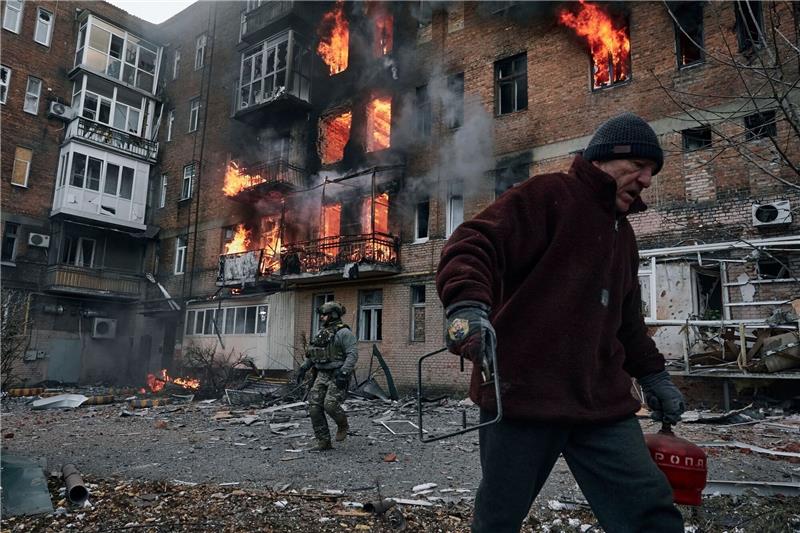 Krieg gegen die Ukraine: So ist die Lage Ein Anwohner verlässt in Bachmut sein Wohnhaus, das nach einem Beschuss in Flammen steht.