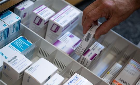 Ein Apotheker holt eine Medikamentenverpackung aus einer Schublade in einer Apotheke.