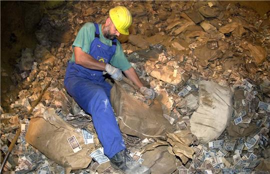 Ein Arbeiter öffnet in einem unterirdischen Stollen im Juni 2002 einen Sack mit altem DDR-Geld. Foto: Peter Förster/dpa