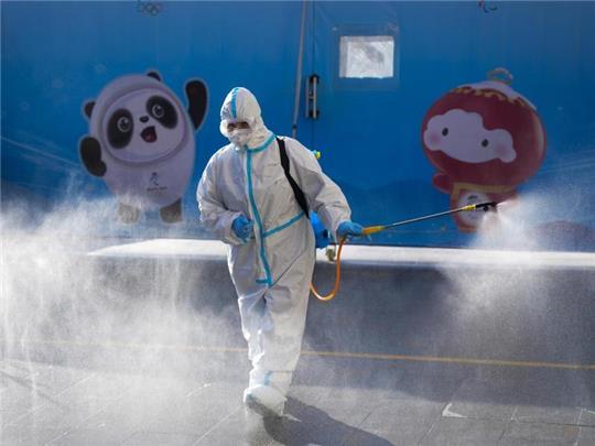 Ein Arbeiter versprüht Desinfektionsmittel vor einem Hotel in Peking. Foto: Natacha Pisarenko/AP/dpa