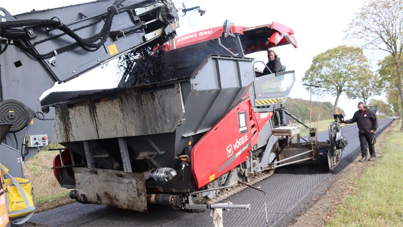 Ein Fertiger bringt Asphalt auf eine abgefräste Straße auf.
