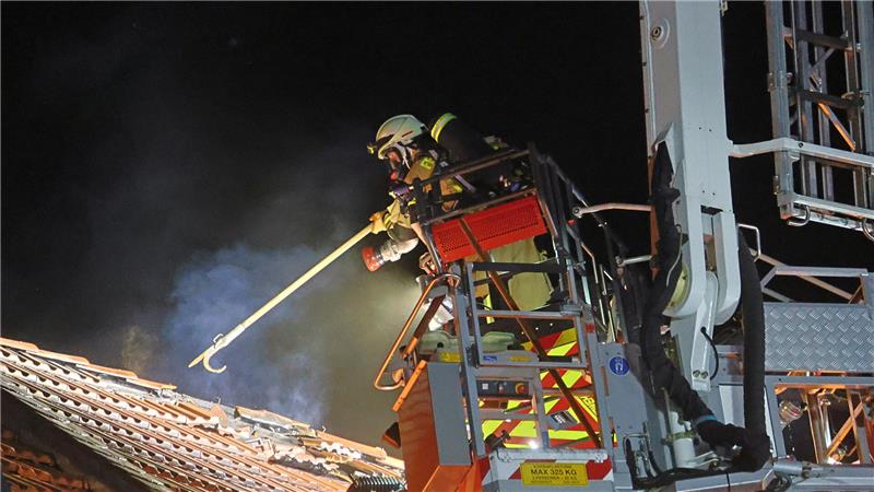 Ein Atemschutzträger der Feuerwehr öffnet das Dach mit einem Werkzeug.