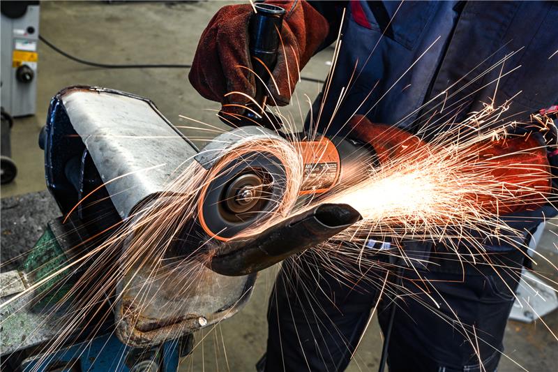 Ein Auszubildender im Kfz-Handwerk schneidet in einem Ausbildungszentrum mit einer Flex einen alten Auspuff auf. Der IG-Metall-Chef Thorsten Gröger fordert mehr Perspektiven für Auszubildende. Foto: Felix Kästle/picture alliance/dpa