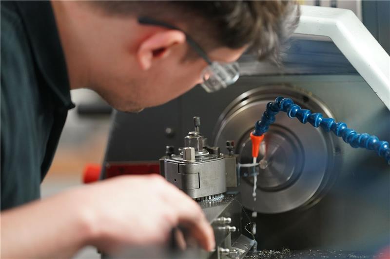Ein Auszubildender zum Zerspanungsmechaniker arbeitet an einer Drehmaschine. Viele Unternehmen in Deutschland werden auch in diesem Jahr wieder Probleme haben, Auszubildende zu finden (Symbolbild).