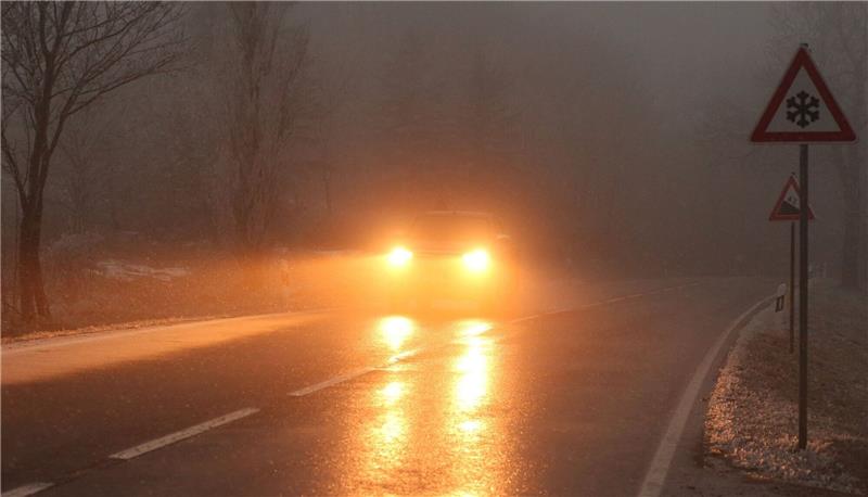 Vorsicht Glatteis: Gefahr auf Straßen und Wegen Ein Auto fährt bei Glatteis und Nebel über eine Straße.