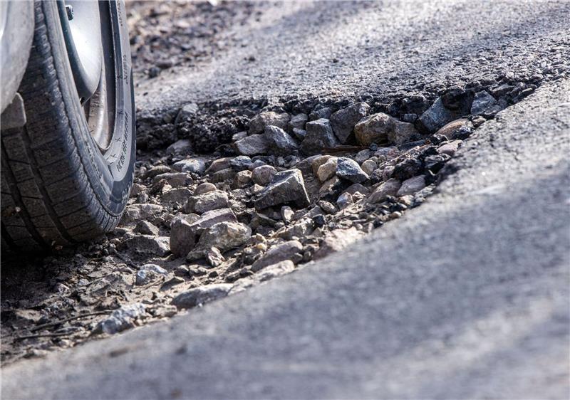 Ein Auto fährt durch ein Schlagloch: Immer mehr Unternehmen klagen über die teilweise marode Straßen in Deutschland.