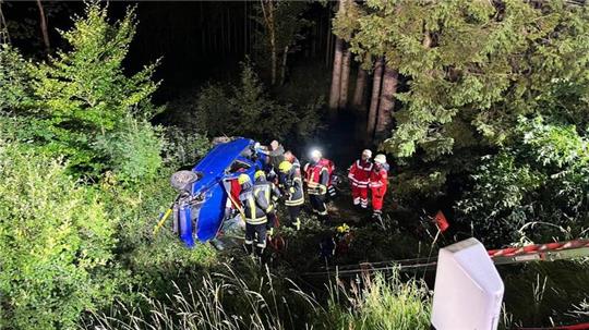 Ein Auto stürzt in der Nacht einen Abhang hinunter.